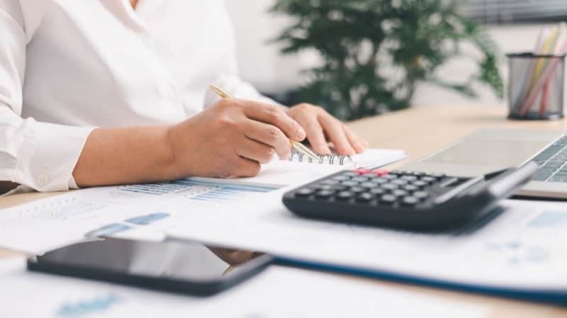 Meta Advantage+ kampanya bütçesini planlayan eller, hesap makinesi ve performans raporları